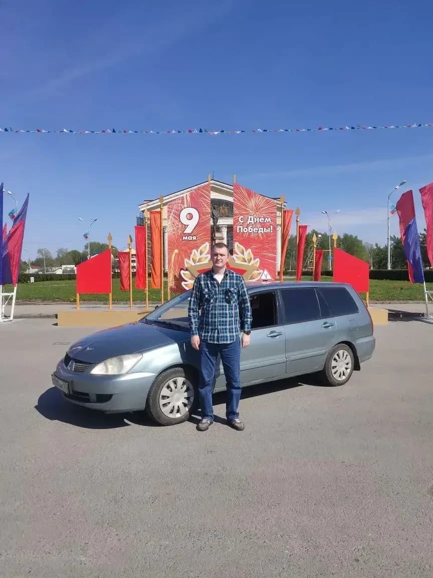 Инструктор Артём Андреевич у голубого учебного автомобиля Mitsubishi Lancer