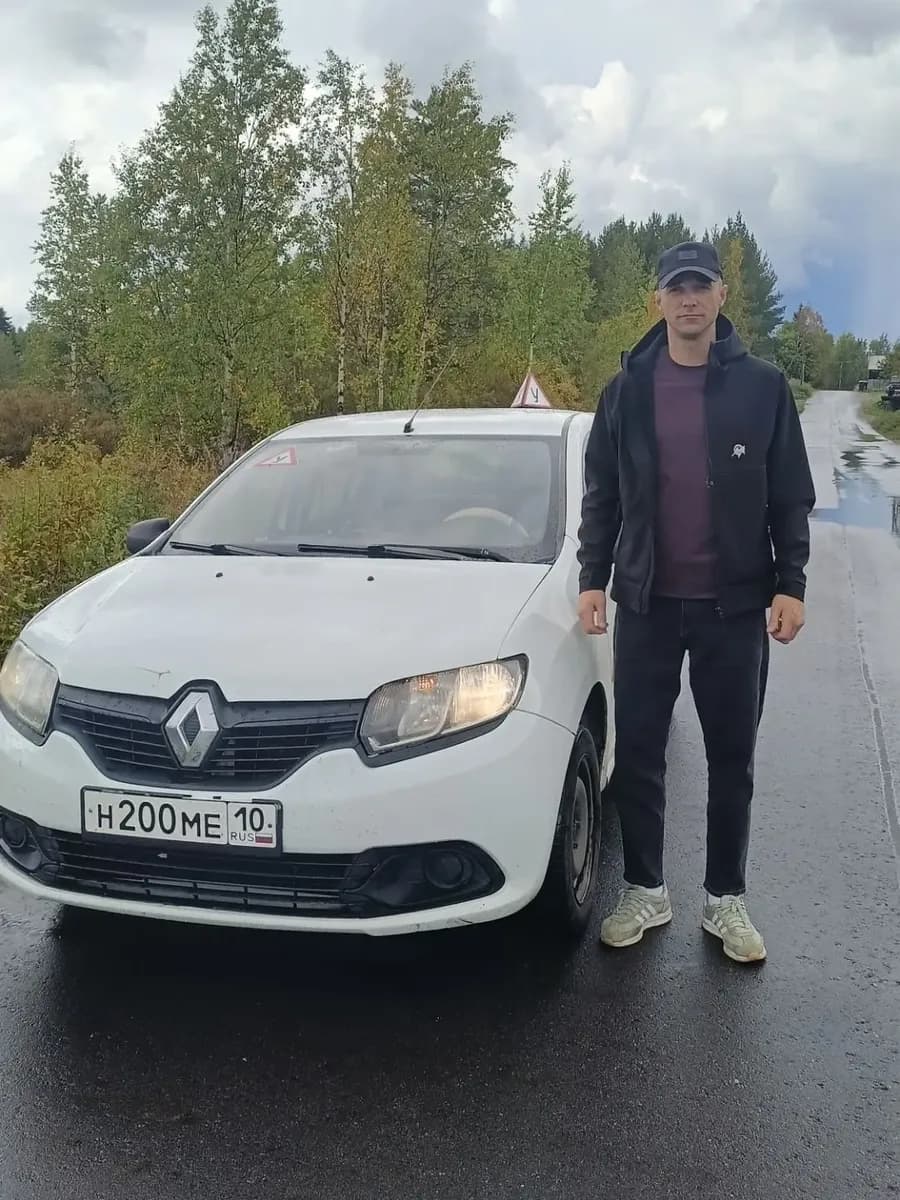 Инструктор Максим Валерьевич у белого учебного автомобиля Renault Logan